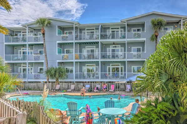 A multi-story hotel with a swimming pool and outdoor seating.