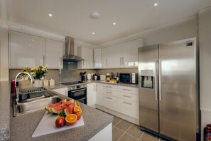 Une cuisine moderne équipée d’appareils électroménagers en acier inoxydable, d’un plan de travail en granit et d’une grande variété de fruits et de légumes.