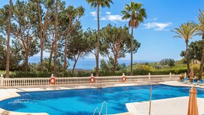 A swimming pool with a view of the ocean, surrounded by palm trees and a white fence. - Calahonda Elegance With Pool And Sea View, Mijas Costa, Spain (Mijas Costa)