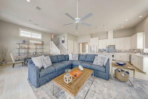 A spacious living room with a blue sectional sofa, a wooden coffee table, and a ceiling fan.
