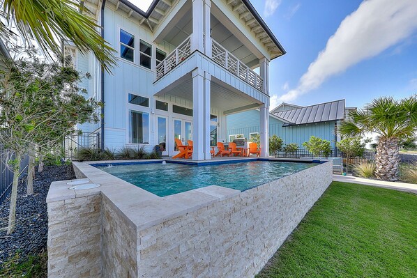 A two-story house with a swimming pool, outdoor seating, and a well-maintained garden.