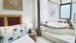 A modern bathroom with a freestanding bathtub, a large mirror, and a decorative wall piece. - Reef @ Aanuka Beach Resort Pool / Spa / Tennis (Coffs Harbour)