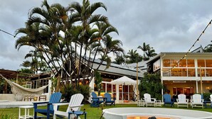 A tropical resort with outdoor seating, palm trees, and a pool area. - Reef @ Aanuka Beach Resort Pool / Spa / Tennis (Coffs Harbour)