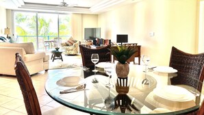 A well-lit living room with a round glass table set for dining, a sofa, and a television in the background. - Luxurious Waterfront Stay w/ Large Sun Deck (Providenciales)