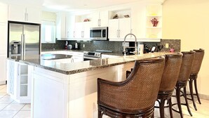 A modern kitchen with white cabinets, stainless steel appliances, and a granite countertop. - Luxurious Waterfront Stay w/ Large Sun Deck (Providenciales)