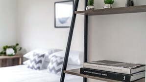 A bedroom with a bed, pillows, a nightstand, a bookshelf, and a framed picture on the wall. - Bright & Peaceful Top-Floor Retreat with Harbour Views (Manly)
