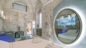 A spa room with stone walls, a round mirror, a massage table, and a TV screen displaying information. - Bed & Breakfast in Ostuni with 1 bedrooms sleeps 2 (Ostuni)