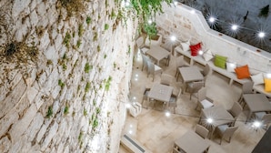 An outdoor seating area with tables and chairs, a stone wall, and string lights. - Bed & Breakfast in Ostuni with 1 bedrooms sleeps 2 (Ostuni)