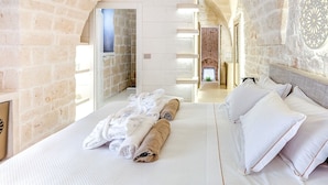 A room with a stone wall, a bed with white linens, and a view of a courtyard. - Bed & Breakfast in Ostuni with 1 bedrooms sleeps 2 (Ostuni)