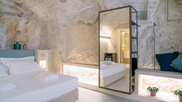 A bedroom with a stone wall, a bed with white linens, a large mirror, and a bedside table with a plant. - Bed & Breakfast in Ostuni with 1 bedrooms sleeps 2 (Ostuni)