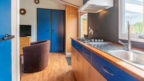 Une cuisine moderne avec des meubles en bois, un évier en acier inoxydable et une fenêtre qui laisse entrer la lumière naturelle.