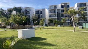 A modern residential building with multiple balconies, surrounded by well-maintained lawns and trees.