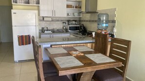 A compact kitchen with a refrigerator, microwave, stove, and water dispenser.