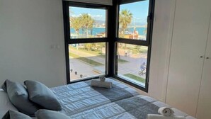 A hotel room with a large window offering a view of a beach and palm trees. - MALAGA BEACHFRONT PARADISE (Malaga)