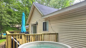 Ein Whirlpool mit einer Holzterrasse und einem Haus im Hintergrund.