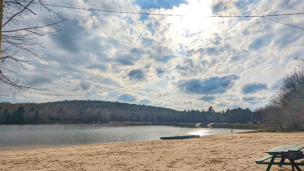 Ein Sandstrand mit Picknicktisch und einem Boot im Wasser.