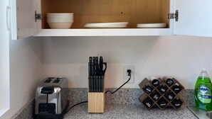 Eine Küche mit einem Holzkorpus, einem Toaster, einem Messerblock und einem Weinkühler.