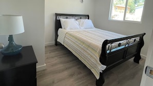 Ein Schlafzimmer mit Bett, Nachttisch, Deckenventilator, Klimaanlage und Fenster.