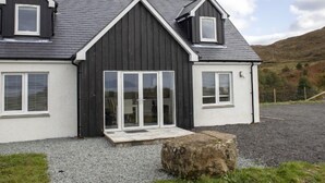 A modern two-story house with a dark exterior, white trim, and a sloped roof.