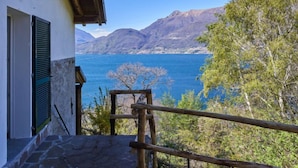 A stone staircase leading to a balcony overlooking a lake with mountains in the background.