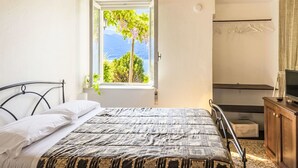 Ein Schlafzimmer mit Bett, einem Fenster mit Blick, einer Holzbalkendecke und einem Badezimmer mit Dusche.