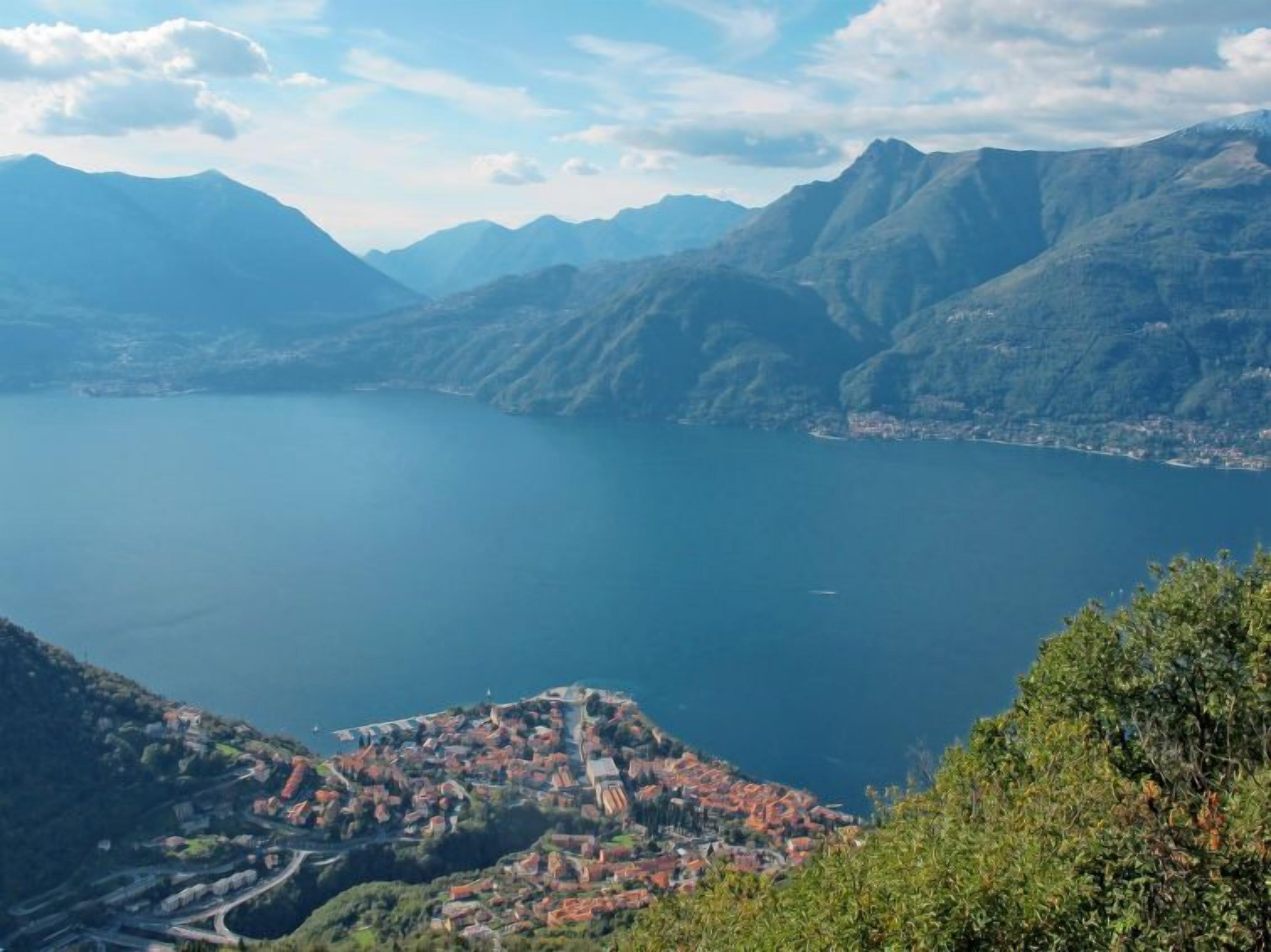 Un paisaje montañoso con un lago y un pueblo enclavado en el valle.