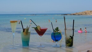A table with various drinks at a beachside location. - Antonios Village (Pineios)