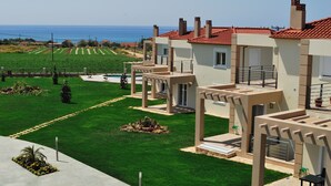 A residential area with modern houses, a well-maintained lawn, and a view of the sea. - Antonios Village (Pineios)