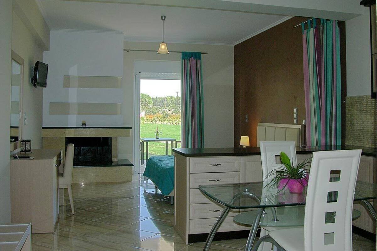 A modern kitchen with a dining area, a TV mounted on the wall, and a view of the outdoors.