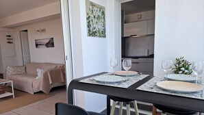 Ein Essbereich mit Tisch für zwei Personen, Stühlen und einer Küche im Hintergrund.