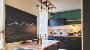 Une cuisine moderne avec des meubles de couleur sombre, une table en bois et un tableau représentant des montagnes.