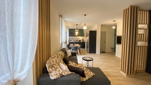 Un salon moderne avec un canapé, un coin repas et une cuisine en arrière-plan.