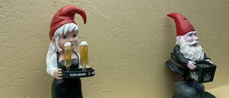 Dos figuritas de gnomos sobre una estantería frente a una pared con textura.