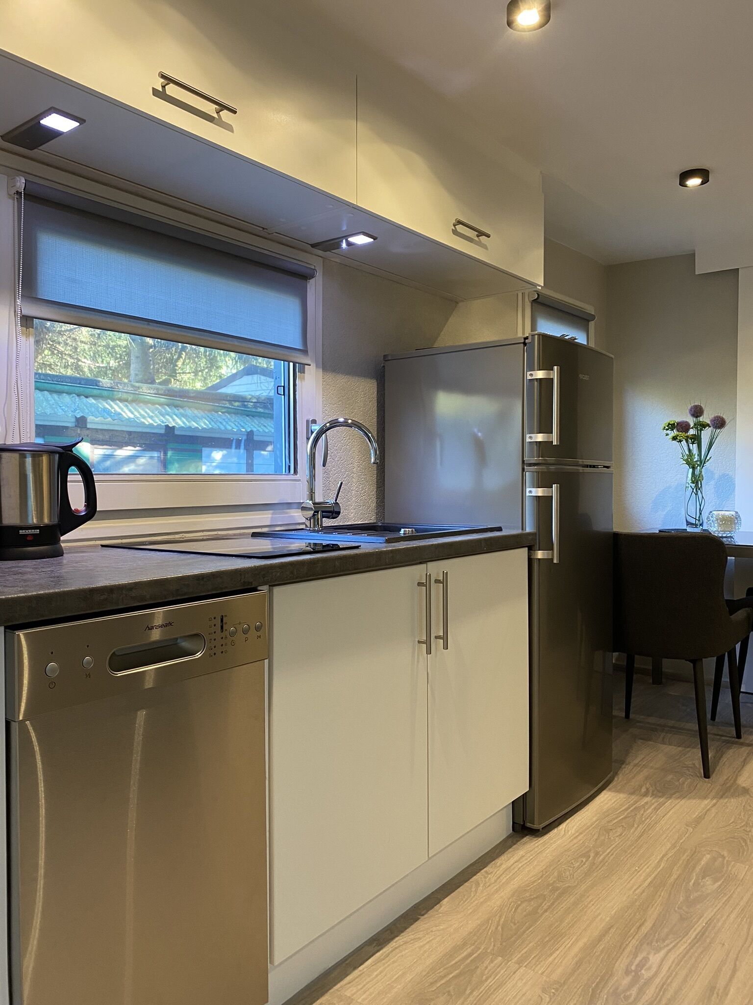 A modern kitchen with a dishwasher, stainless steel appliances, and a window with a view of a traditional building.