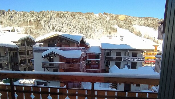 A snow-covered mountain town with wooden buildings and a sign for 'Delway Sport Location Skishop'. - Studio at Les Gets ski lift, modern comfort (Les Gets)