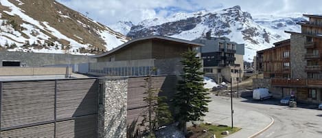 A modern building with a stone facade, a metal fence, and a view of snow-capped mountains.