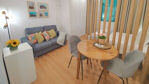 Un salon moderne avec un canapé gris, une table à manger et des chaises, ainsi qu'une cloison en bois.