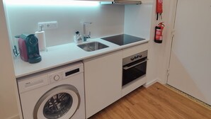 Une cuisine compacte équipée d’un lave-linge, d’un lave-vaisselle, d’un évier et d’un four encastré.