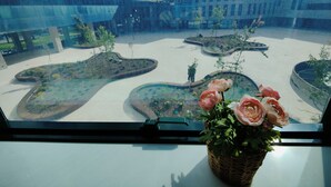 Une vue d’une cour intérieure dotée d’une architecture moderne, d’un ciel dégagé et d’une plante en pot ornée de fleurs.