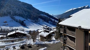 Een bergdorp bedekt met sneeuw, met traditionele houten huizen, een heldere lucht en uitzicht op de omliggende bergen.