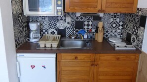 Een functionele keuken met een magnetron, koffiezetapparaat en een kleine koelkast.