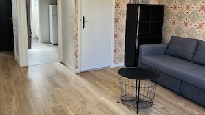 A spacious living room with a grey sofa, a black coffee table, and a patterned wallpaper. - Appart PARIS Sud★ calm & bright - RER B 2 minutes (Cachan)