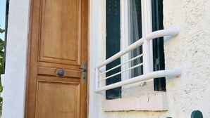 A wooden door with a metal handle, a window with a white metal guard, and a green-painted gate. - Appart PARIS Sud★ calm & bright - RER B 2 minutes (Cachan)