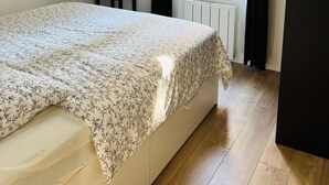 A bedroom with a bed, a hanging light fixture, a radiator, and a window with curtains. - Appart PARIS Sud★ calm & bright - RER B 2 minutes (Cachan)