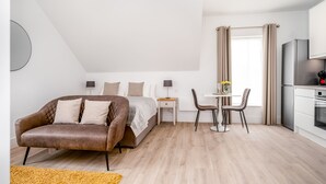 Ein modernes Schlafzimmer mit Bett, Sofa, Schreibtisch und Essbereich.