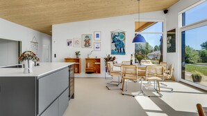 A modern kitchen with a central island, wooden cabinets, and a dining area with a round table and chairs. - Beach front home in Haderslev (Haderslev)