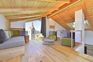 Une pièce de style loft avec des poutres en bois, un canapé, un fauteuil vert et une table basse en bois.