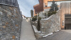 Eine steinerne Treppe führt zu einem Holzhaus mit einem Balkon.
