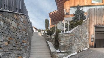 Eine steinerne Treppe führt zu einem Holzhaus mit einem Balkon.