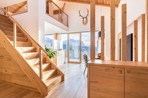 Un escalier en bois menant à un balcon offrant une vue sur les montagnes, un bureau en bois et une décoration faite de bois de cerf.